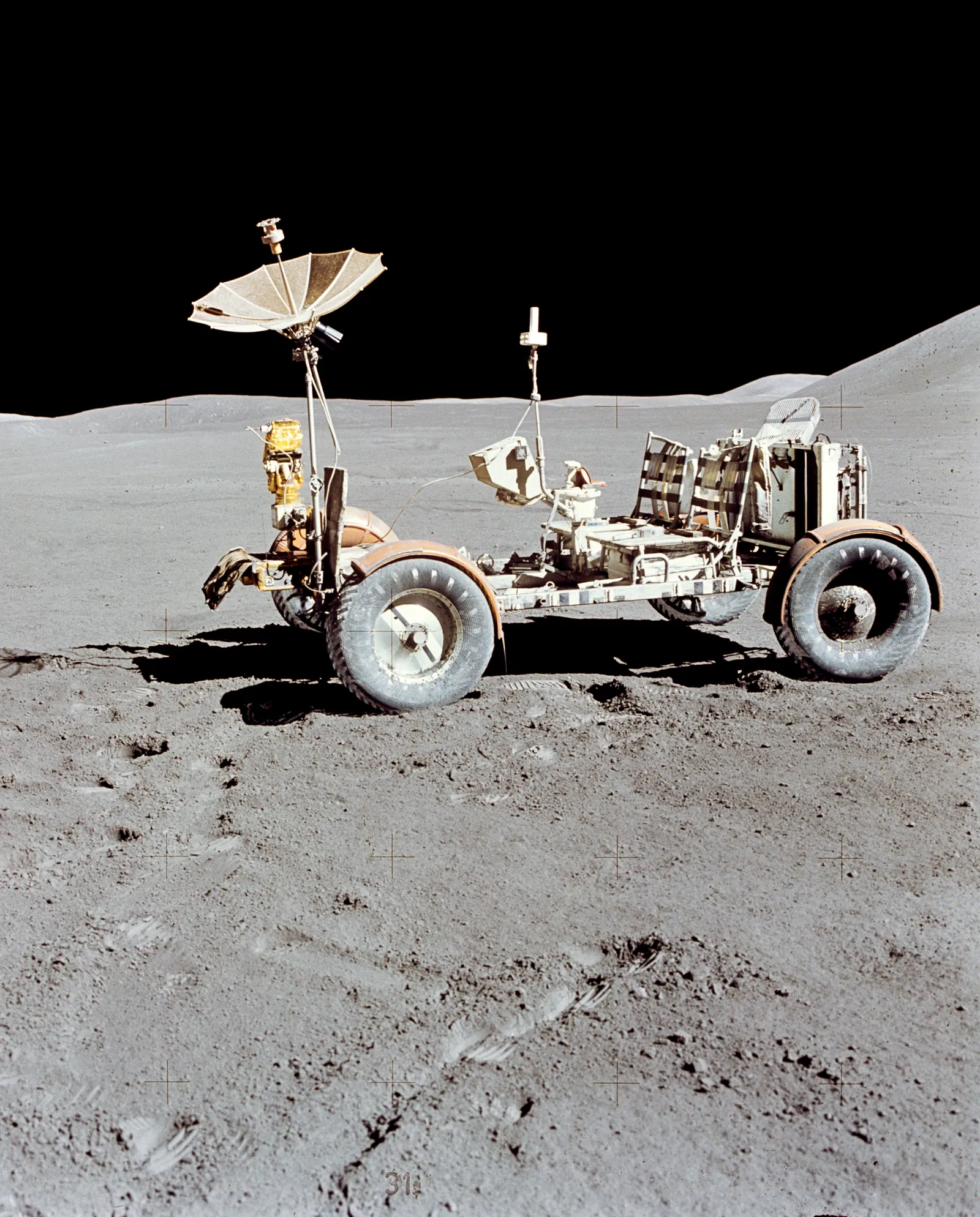 A lunar roving vehicle standing alone on the surface at the Hadley–Apennine site, Mount Hadley on the horizon behind it.